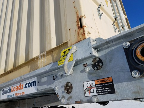 A shipping container locked onto the bed of a QuickLoadz trailer.